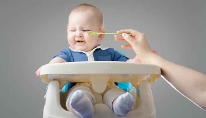 Hình ảnh một em bé nhỏ đang chán ăn, quay mặt đi trước bát bột, thể hiện giai đoạn biếng ăn sinh lý phổ biến ở trẻ nhỏ
